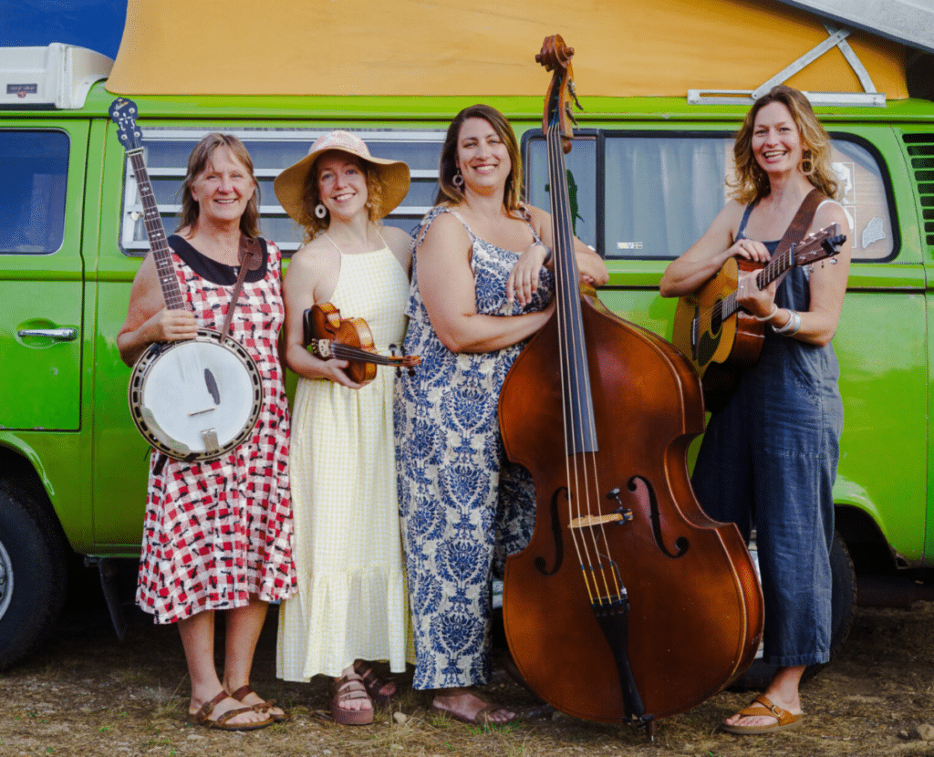 The Hazel Project Band photo with banjo, fiddle, bass, and guitar in front of a green camper van.